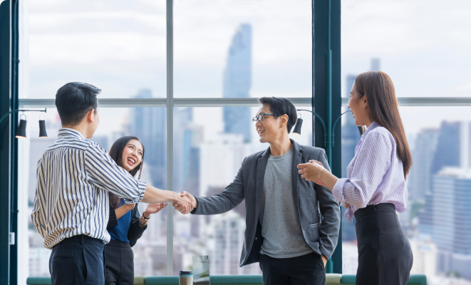 Business professionals shaking hands and smiling during a meeting in a modern office with city view.